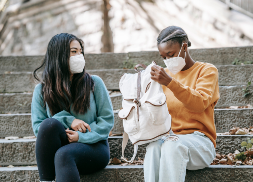 young people sitting in stairs outside looking inside a backpack